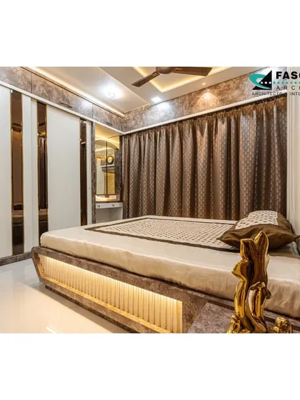 This bedroom in Bhiwandi features a unique bed with an illuminated base and a backdrop of textured wallpaper and cove lighting. The sliding wardrobe with mirrored strips enhances the sense of space and adds a modern touch.