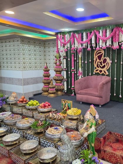 A baby shower (Seemantham) setup with a pink and green theme, featuring a mother-and-child motif on the backdrop.