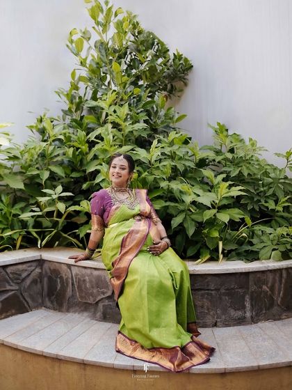 A beautiful portrait of an expecting mother seated in a garden. Dressed in a traditional green silk saree, she embodies the serene glow of pregnancy.