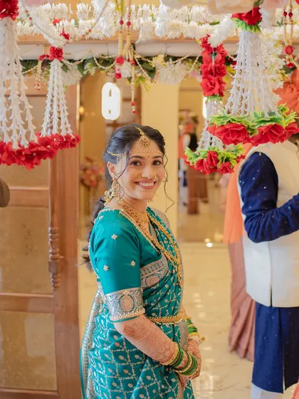 A candid shot of the bride during her wedding festivities, looking radiant in a teal blue saree. Her natural smile shows how comfortable and beautiful she feels.