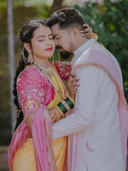 A loving embrace with soft, natural lighting, showcasing the beautiful pink and yellow colors of the bride's saree.