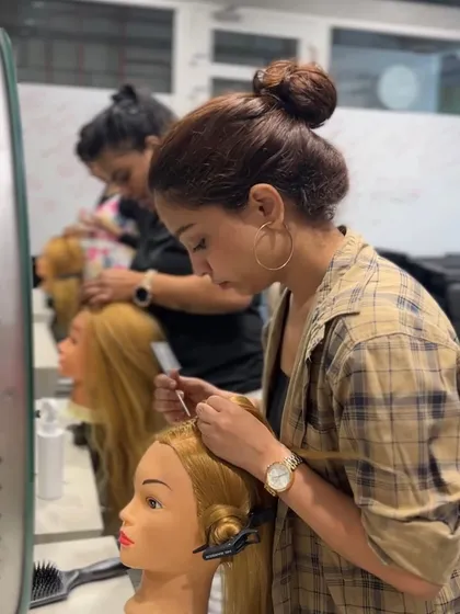 A student practices an elegant updo on a mannequin, a key skill for bridal and event hairstyling.