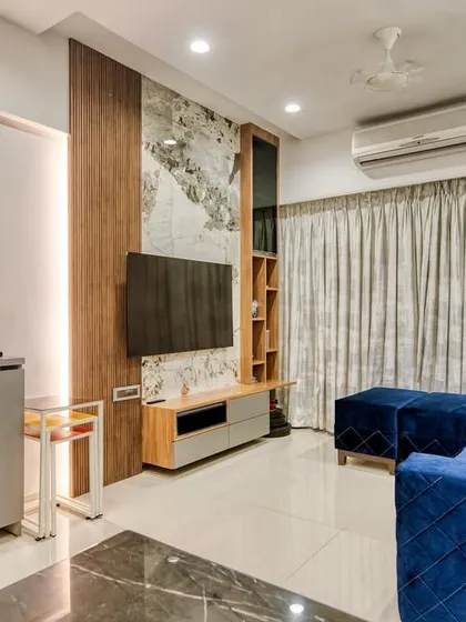 This sleek and stylish TV unit seamlessly blends functionality with modern aesthetics. The combination of wood, marble-finish panels, and a blue sofa creates a vibrant living space.