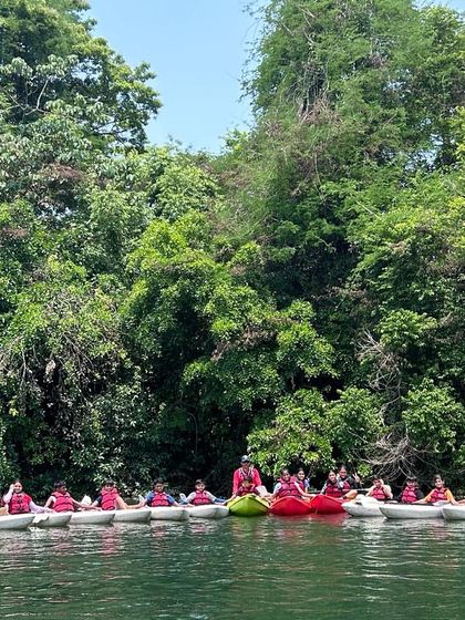 A large group of campers in kayaks and rafts assemble on the river, showing the scale of our Dandeli water sports program.