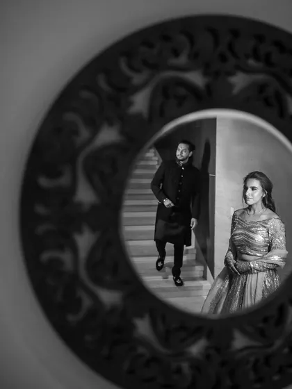 A creative and artistic shot, capturing the couple's reflection in an ornate mirror. This black and white photo adds a touch of timeless elegance and intrigue to their engagement story.