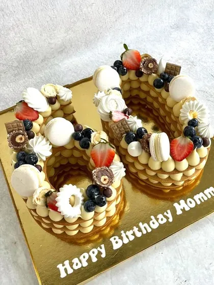 A cream tart cake for a 60th birthday. This one is decorated with macarons, fresh berries, and little pieces of chocolate.
