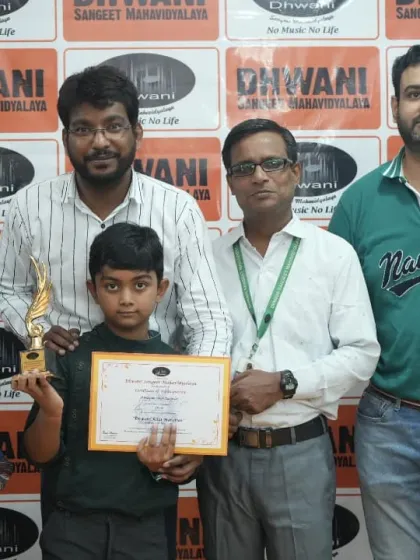 A young student, his parents, and his teacher pose with his art competition trophy.