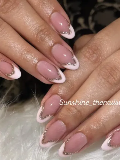 A modern French manicure with a white base and a silver glitter V-shape.