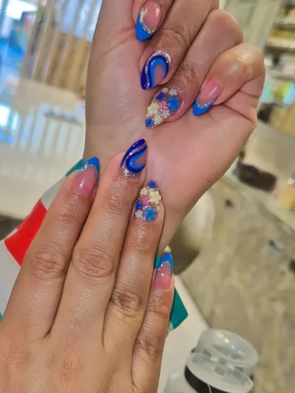 A modern twist on the classic French manicure. This design features a bold blue French tip, silver glitter accents, abstract swirls, and intricate 3D floral embellishments on an almond-shaped nail. It’s a great example of how I combine multiple techniques into one cohesive, artistic set.