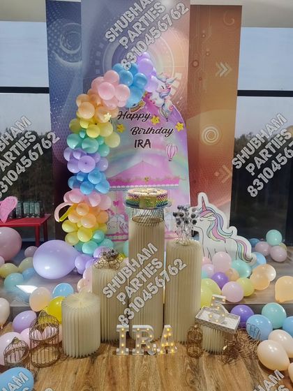 A magical unicorn themed birthday decoration with a pastel rainbow balloon arch and a unicorn cutout.
