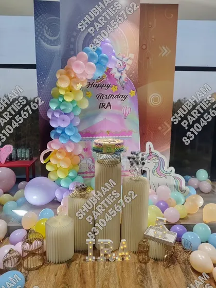 A magical unicorn themed birthday decoration with a pastel rainbow balloon arch and a unicorn cutout.