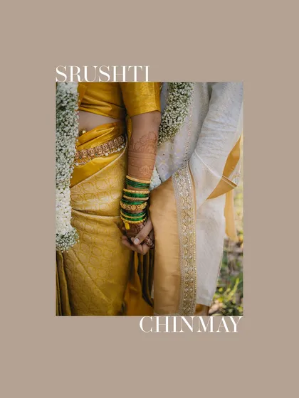 A close-up detail shot of a couple holding hands, showcasing the bride's colorful bangles and the groom's traditional attire. It's a simple yet powerful symbol of their union.