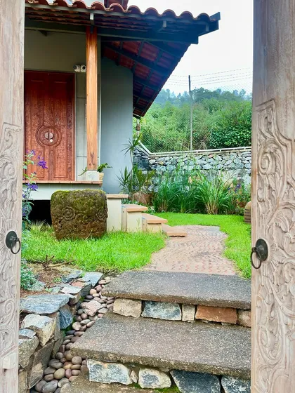 The entrance to a private space at the TARA resort, framed by intricately carved wooden doors. This moment of entry is designed to be a transition, moving from the open landscape into a personal sanctuary, highlighting our use of reclaimed materials and traditional craftsmanship.