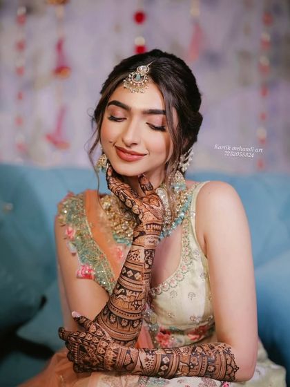 A graceful pose by a beautiful bride, her mehandi-adorned hand resting on her cheek.
