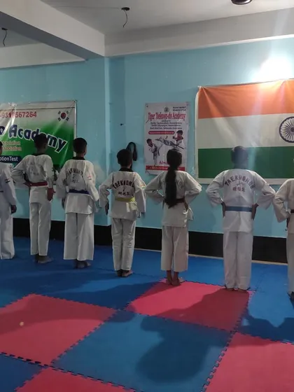 Students standing at attention, facing the Indian flag. Discipline and respect are the first things taught at my academy.