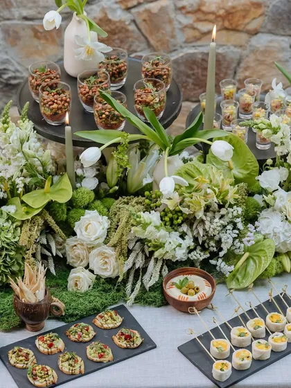 A bountiful view of the appetizers on the Earth Table. Various canapés, dips, and small bites are artfully arranged among the lush floral runner.