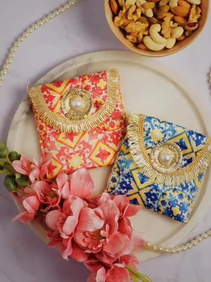 A charming arrangement of small, ornate pouches with pearl necklaces and pink flowers. The styling is delicate and pretty, suggesting these accessories are perfect for gifting or special occasions.