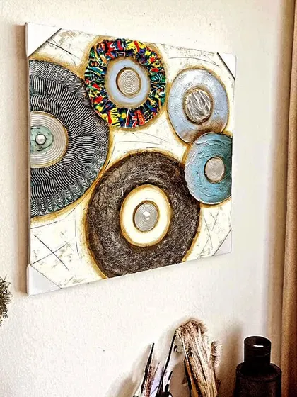 This 3D embossed canvas painting features a playful collection of abstract, multi-textured circles. The mix of colors and materials on this 32x32 inch frame creates a unique and contemporary piece of art.