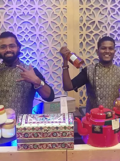 Two of our smiling bartenders, dressed in traditional printed vests, stand ready to serve. Their attire is chosen to complement the Sufi theme of the event perfectly.
