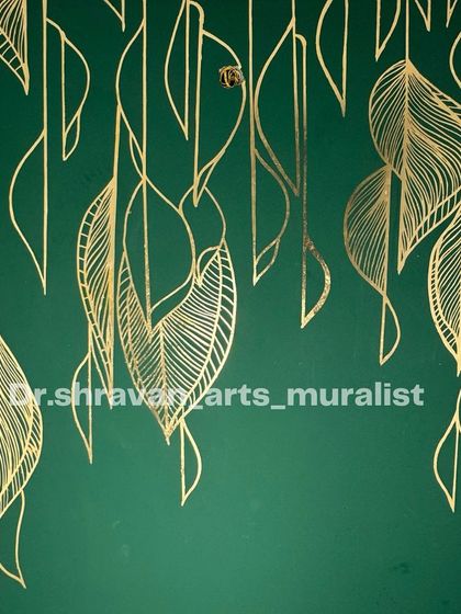A simple yet stunning gold foil mural on a staircase wall. The delicate, falling leaves are rendered in clean gold lines against a dark green background, creating a very chic and modern look.