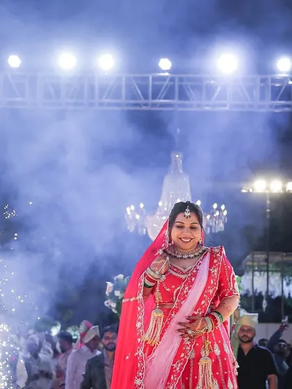 The bride's grand entrance, walking towards her future through a path of smoke and fireworks. This is a moment of anticipation and excitement, beautifully captured before she meets her groom.