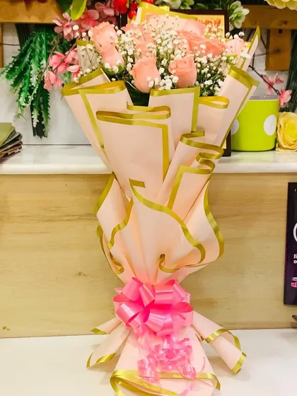 A side view of the peach rose bouquet, showing the layered effect of the Korean-style wrapping and the bright pink bow.