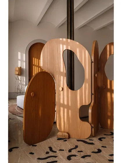 Our 'Hide N Seek' screen is furniture that invites play. Designed to divide a large suite into a salon and bedroom, its amoebic wooden panels have organic cutouts that frame views and create intriguing vignettes. It’s a sculptural piece that is both a space divider and an interactive art form.