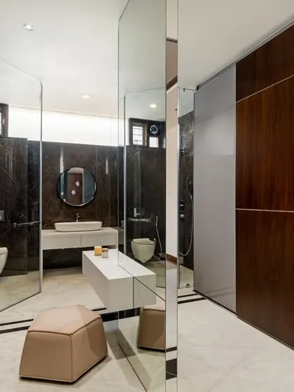 The walk-in closet and dressing area features mirrored and timber-paneled wardrobes that create a sense of expanded space. The design leads into the master bathroom, which is clad in dark, dramatic stone.