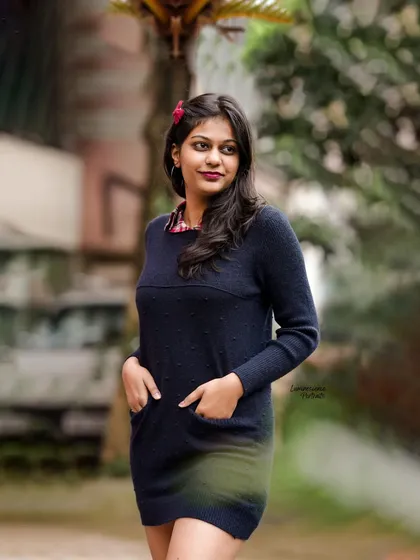 A confident pose with hands in pockets, this portrait captures a relaxed and stylish vibe in a simple black dress.