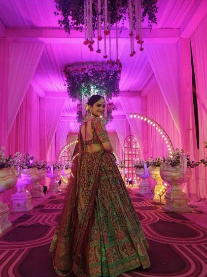 A happy client at her wedding, walking down an aisle decorated with flowers. The back of the blouse and the full lehenga look stunning.