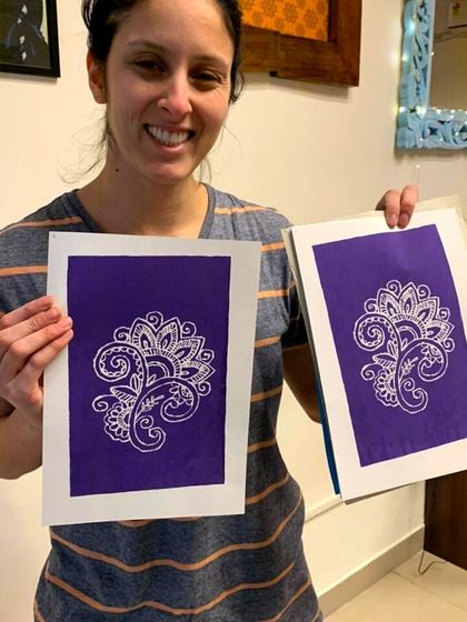 A happy student showing off her two identical paisley prints, demonstrating the magic of replication in printmaking.