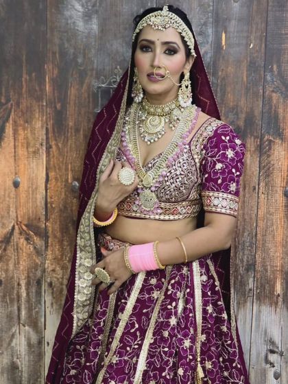A bride in a deep purple lehenga, showcasing a layered silver and gold-toned jewellery set. This is a great example of a non-traditional color combination.