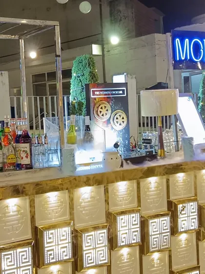 This is a stylish molecular bar setup with an illuminated glass block front. The 'Moleculer' neon sign and organized top-shelf liquors show a professional and appealing station.