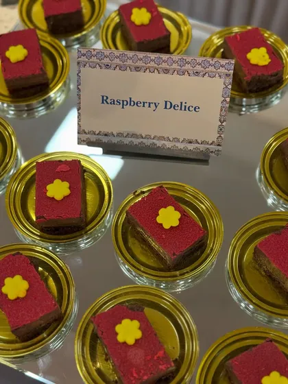 Our Raspberry Delice, a multi-layered pastry with a vibrant raspberry flavour. The delicate flower decoration adds a touch of elegance to this delicious treat.