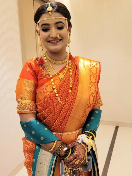 An orange silk saree draped in the traditional Maharashtrian style for this bride's wedding ceremony.