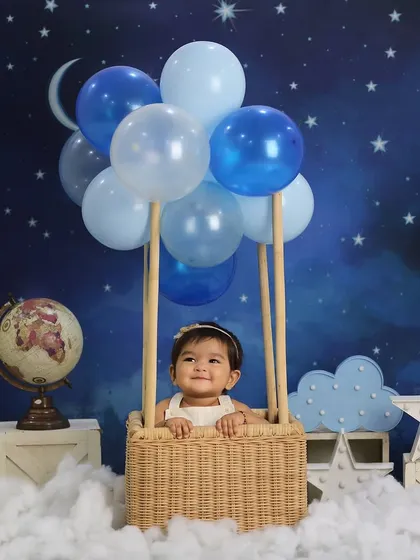 A different angle from the popular hot air balloon theme. This shot shows the little one peeking over the basket, creating a sense of adventure and wonder.