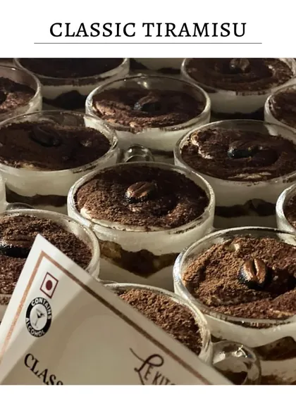 My Classic Tiramisu, served in individual glass cups. Layers of coffee-soaked ladyfingers and creamy mascarpone are dusted with cocoa powder and topped with a coffee bean.