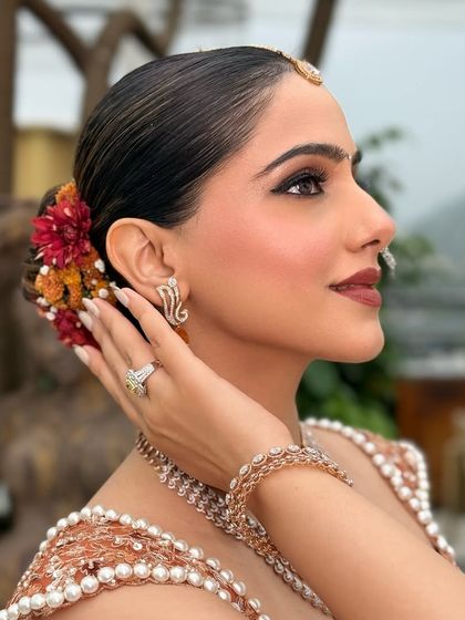 A view of the complete look from the side, showing the sleek bridal bun adorned with fresh flowers. My team and I handle both hair and makeup to create a cohesive, stunning look.