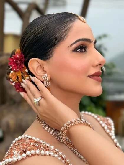 A side view of a sleek bun with a pop of color from fresh flowers. This shows how we can customize a classic hairstyle to match your outfit and personality.