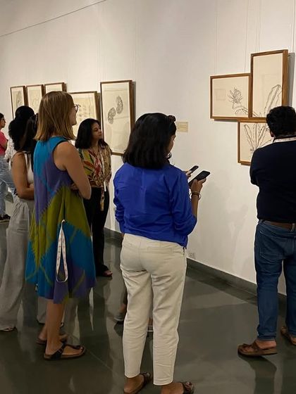 The MAP team viewing the framed drawings on the wall during their guided tour of the exhibition.