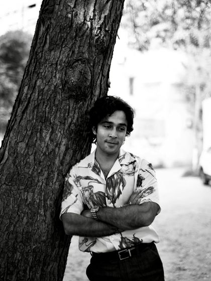 A gentle black and white portrait of Zahan Kapoor leaning against a tree. The soft focus and his relaxed expression create a feeling of calm.