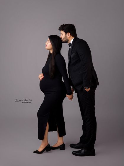 A chic and modern couple's portrait. The husband's tender kiss on his wife's forehead is a timeless gesture of love, captured with a contemporary feel.