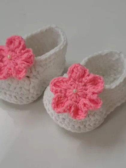 These simple white booties are brightened up with a vibrant pink flower, making them a versatile accessory for many outfits.