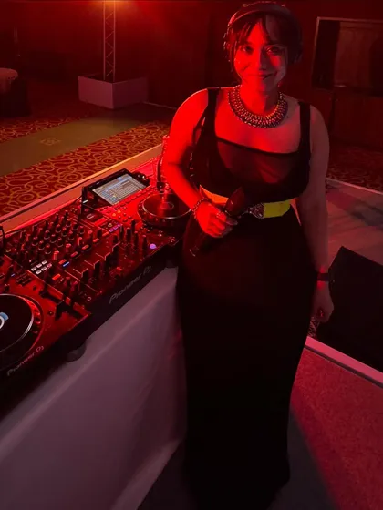 Ready to play at a formal event, standing by my Pioneer mixer. The red ambient lighting set a warm and energetic mood for the evening.