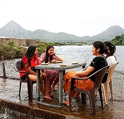 It's not all high-energy action. Our campsites offer serene spots to relax and connect. These guests are enjoying a quiet moment at a table set right by the water's edge, with stunning mountain views in the background.