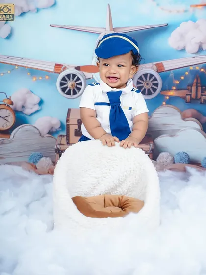Ready for takeoff. This little pilot is all smiles in our aviator-themed setup, complete with clouds and vintage airplanes.