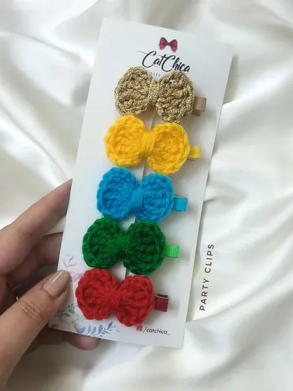 This set of 'Party Clips' features five small crochet bows in bright, festive colors, including a sparkly gold one.