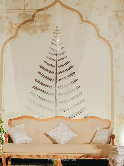 A detail of the reception lounge backdrop, featuring a mirrored tree motif inside a classic Indian arch. This artistic element adds a touch of modern elegance to the traditional design.