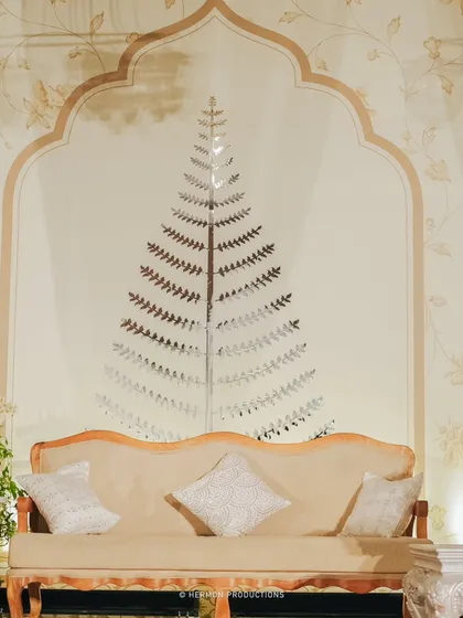 A detail of the reception lounge backdrop, featuring a mirrored tree motif inside a classic Indian arch. This artistic element adds a touch of modern elegance to the traditional design.