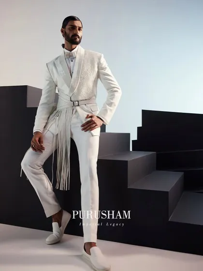 I believe white is a power statement. This ensemble redefines the classic white suit with a modern, architectural silhouette, featuring a structured jacket with a dramatic, fringed belt. It is a look for the man who appreciates classic tailoring but demands a contemporary edge.